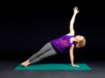 Woman doing side plank pose on Yoga mat