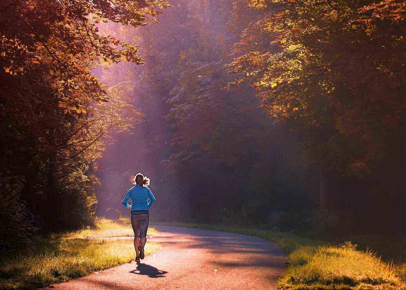 Woman running down country road in sun