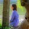 Woman sitting on tree branch meditating
