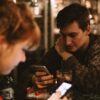 two people in restaurant both focused on their phones